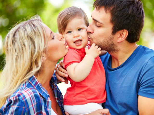 Careful parents kissing their small daughter