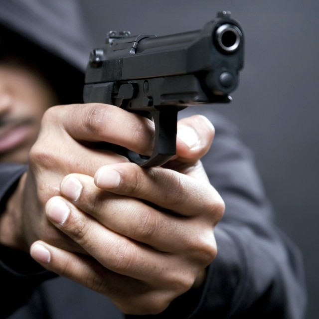 Man pointing a gun at co workers