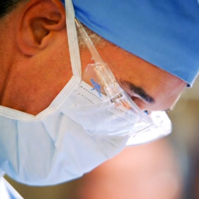 A group of surgeons and nurses perform an operation.