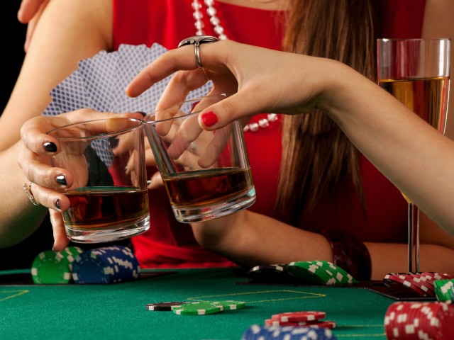 Women proposing a whiskey toast while in a casino